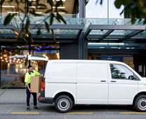Delivery person standing behind light commercial vehicle