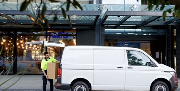 Delivery person standing behind light commercial vehicle