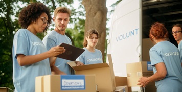 Happy Team of Young Adult Volunteers Loading Meal Rations and Humanitarian Donations for Community in Need into a Van