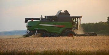 Harvester harvests wheat in the field at sunset closeup. Agriculture banner concept
