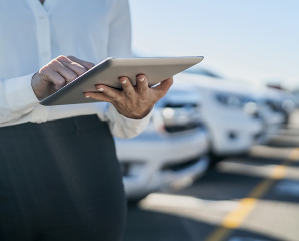 Midsection of car saleswoman using digital tablet at dealership parking lot Midsection of car saleswoman using digital tablet at dealership parking lot
