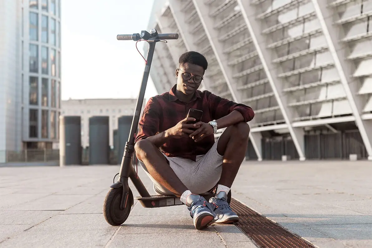 Person sitting on parked eScooter in a city setting