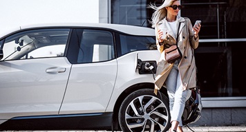 Women leaning on EV whilst charging