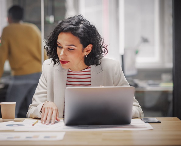 business-woman-sitting-at-desk-in-front-of-laptop-reviewing-paperwork business-woman-sitting-at-desk-in-front-of-laptop-reviewing-paperwork