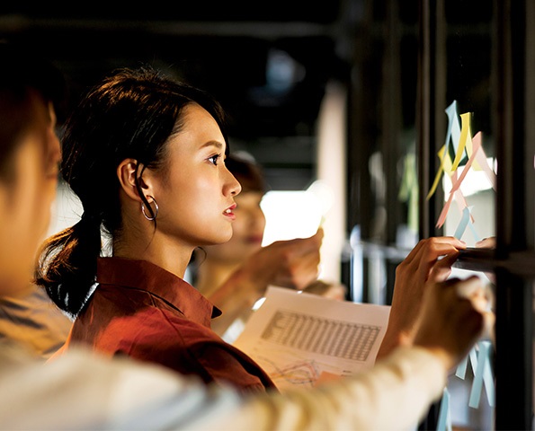 female-professional-brainstorming-looking-at-post-it-notes-in-office-setting