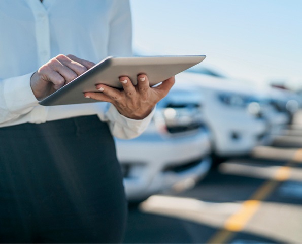 midsection-of-car-saleswoman-using-digital-tablet-at-dealership-car-park midsection-of-car-saleswoman-using-digital-tablet-at-dealership-car-park