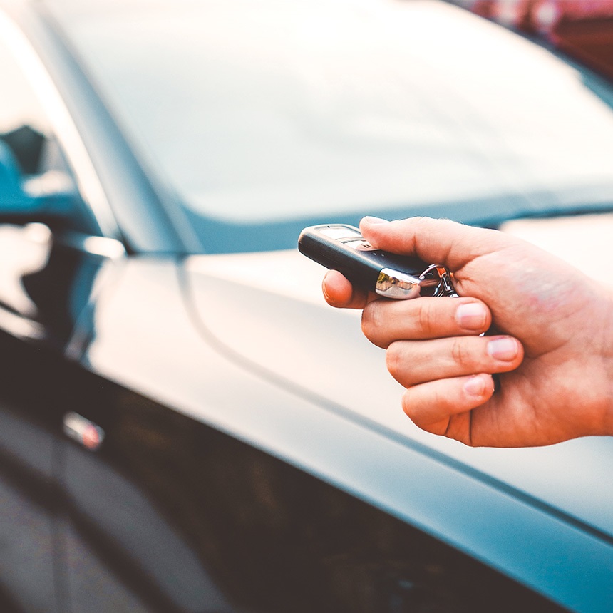 person-holding-car-key-with-car-in-the-background