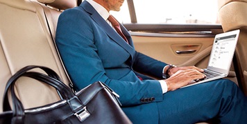 professional-in-car-backseat-on-laptop