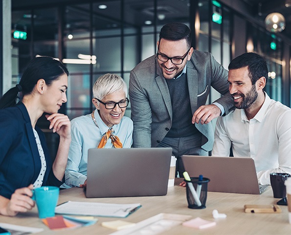 team-of-staff-in-meeting team-of-staff-in-meeting-gathered-around-laptop