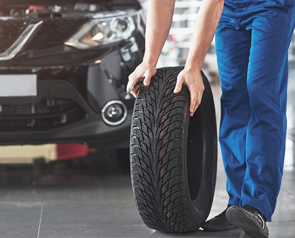 technician-with-blue-workwear-holding-wrench-tyre technician-with-blue-workwear-holding-wrench-tyre