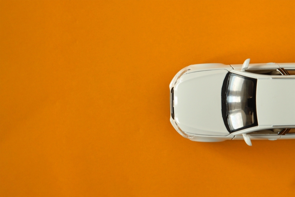 company cars vs cash allowance A car driving across an orange background, top down view