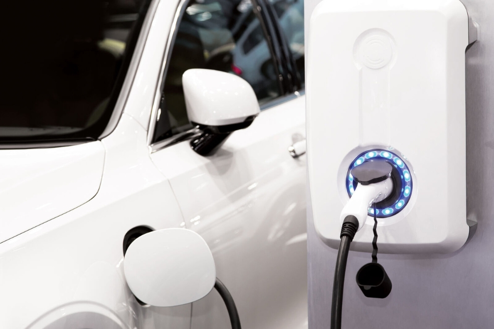 EV accessories home charger Close-up of a white electric car plugged into a modern home EV charger with a glowing blue LED ring.