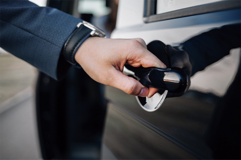hand opening door lease company car Close-up of a person opening the door of a black car, reflecting access to a lease vehicle for business or personal use.