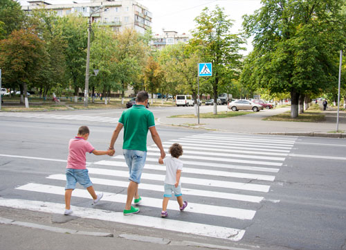 Children crossing the road with parent