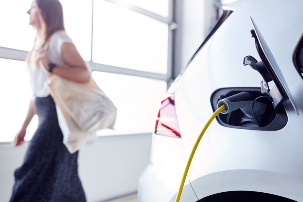 Woman driving PHEV A woman passing by a plug in hybrid car charging